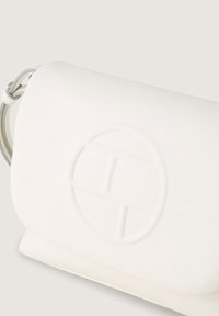 Bílá crossbody taška z umělé kůže s texturovaným povrchem, kruhovým embosovaným logem a elegantním obdélníkovým tvarem. Obsahuje tenký popruh na rameno.