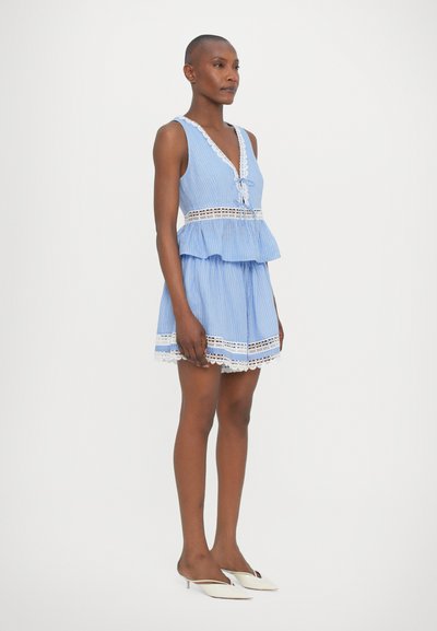 Abito a strisce blu con design a peplum a strati, dettagli in pizzo all'orlo e al collo, dotato di scollatura a V e spalline sottili, abbinato a mule bianche.