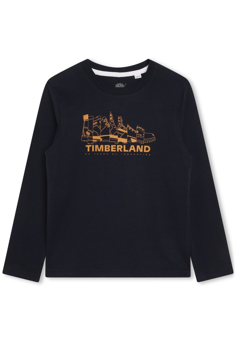 Granatowa koszula z długim rękawem z pomarańczową grafiką przedstawiającą różne buty Timberland oraz napisem "TIMBERLAND 50 lat innowacji" poniżej.