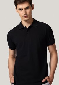 Czarny polo wykonany z bawełny, z kołnierzykiem, krótkimi rękawami i zapięciem na trzy guziki, charakteryzujący się gładką fakturą.