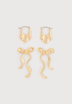 Kaksi paria kultaista korvakorua, toinen pari on pieniä renkaan muotoisia, joissa on rusettiyksityiskohtia, toinen pidempi pari virtaavilla rusettimeleillä.