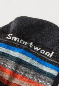 Stickade strumpor i grått, svart och orange med horisontella ränder i blått och grönt. Inkluderar "Smartwool"-logotypen på manschetten. Mjuk textur.