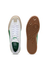 Weiße Sneaker mit grünen Akzenten, ausgestattet mit einer Wildleder-Zehenkappe, schnürbarem Design und einer strukturierten braunen Gummisohle mit kreisförmigen Mustern.