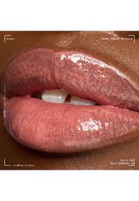 Gloss à lèvres rose brillant avec un léger éclat sur des lèvres entrouvertes, sur une peau de teint moyen-foncé, mettant en valeur la texture naturelle et la brillance.