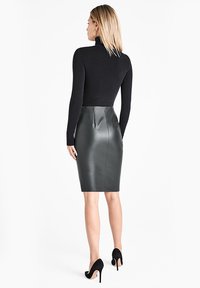 Zwarte coltrui met lange mouwen, gecombineerd met een aansluitende, hoogtailles donkergriijze leren kokerrok met een gladde textuur en naaddetails.