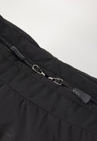 Giubbotto imbottito nero con finitura liscia e opaca, cuciture orizzontali e zip bidirezionale con un tirante testurizzato.