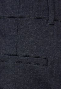 Tessuto grigio scuro con una sottile texture, caratterizzato da un design con tasca piatta e cuciture pulite. Il materiale ha un aspetto fine e tessuto.