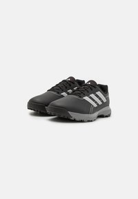 Zapatos deportivos negros que cuentan con material sintético, superficie texturizada, acentos grises y una suela de goma con patrones de tracción.