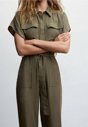 Olivgrüner Overall mit kurzen Ärmeln, Knopfverschluss, zwei Brusttaschen und gebundener Taille. Glatte Textur und lockere Passform.