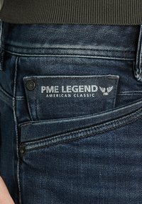 Jean en denim bleu foncé avec une coupe classique, comportant une étiquette indiquant "PME Legend American Classic" et une texture subtile.