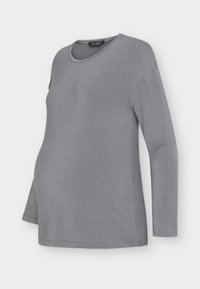 Γκρι μακρυμάνικη μπλούζα από μαλακό ύφασμα, με στρογγυλή λαιμόκοψη και άνετη εφαρμογή, σχεδιασμένη για να προσαρμόζεται σε μια αναπτυσσόμενη κοιλίτσα.