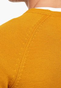 Strickpullover in leuchtendem Gelb, mit einem strukturierten Muster und einem Rundhalsausschnitt, mit sichtbaren Nähten entlang der Schulterpartien.