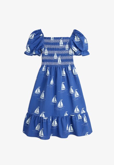 Blå bomullsklänning med korta puffärmar, smockad kropp och rynkad nederkant med ett mönster av vita segelbåtar på en texturerad bakgrund.