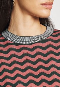 Gebreid top met een golvend patroon in donkergroen en roze, met een geribbelde, gestreepte halslijn. Zachte textuur met een aansluitende pasvorm.