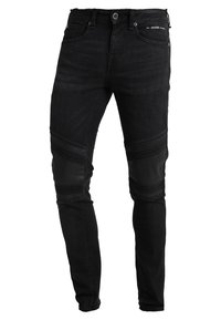 Jeans de mezclilla negra con corte slim, que presentan paneles de rodilla de poliuretano, textura acanalada en los lados y detalles metálicos.