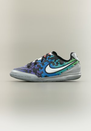Lavtskaftet sportssko med pixeleret mønster i blå, grøn og lilla, sorte snørebånd, stort hvidt Nike-swoosh og grå sål på en ensfarvet baggrund.