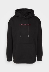 Sudadera negra con capucha y bolsillo frontal, con el texto rosa "BASECAMP FOLLOW THE TRAIL" centrado en el pecho, cuenta con capucha ajustable por cordones.