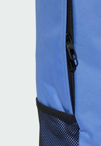 Mochila de tela azul con un cierre negro, bolsillo lateral de malla y textura suave, diseñada para la durabilidad y funcionalidad.