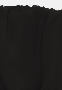 Svart chiffontyg med en mjuk, genomskinlig textur och en något vågig övre kant samt smidig drapering. Inga mönster eller detaljer synliga.