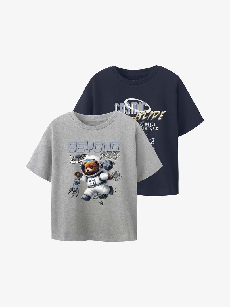 Δύο κοντομάνικα μπλουζάκια, ένα γκρι με μια αρκούδα αστροναύτη και το κείμενο "Πέρα από τα Άστρα", ένα ναυτικό με διαστημικό θέμα και το κείμενο "Κοσμική Ολίσθηση" με σχέδιο.