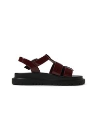 Red patent leather sandals with adjustable straps, a chunky black sole, and an open design. Textured tread for grip and stability.