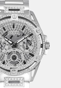 Srebrna ura iz nehrjavečega jekla z teksturirano številčnico, kristalnimi poudarki, več podštevilčnicami in polirano površino. Ima drzne črne kazalce.