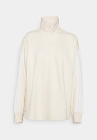 Gräddfärgad tröja med hög krage och halvlång dragkedja. Har ett vitt tre-stripers mönster på ärmarna och en liten logotyp på bröstet.