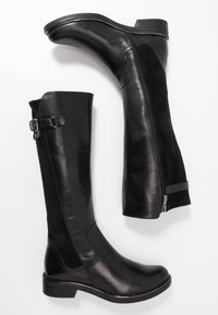 Černé kozačky sahající ke kolenům, s koženým vnějškem a semišovým bočním panelem, se zipem na zadní straně a sloupkovým podpatkem.