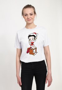 Hvid bomulds t-shirt med trykt tegneserie af en pige med en julestråhat, omgivet af en gaveæske og en lille hund.