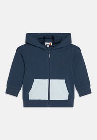 Felpa zip-up color navy con tasca azzurro chiaro. Presenta una texture morbida e un cappuccio con cordino. Logo Timberland sul petto.