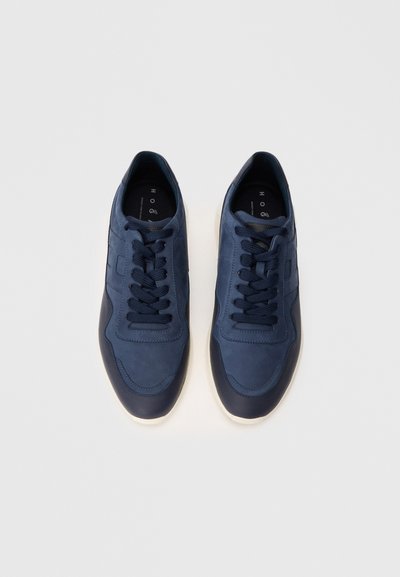 Baskets en cuir bleu marine avec une finition lisse, bout rond, design à lacets, et semelle foncée contrastante. Branding minimal sur les semelles intérieures.