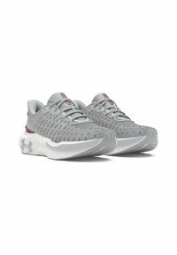 Par de zapatillas de correr de malla gris y burdeos con suelas acolchadas blancas, logo de Under Armour en el talón y parte delantera con cordones.