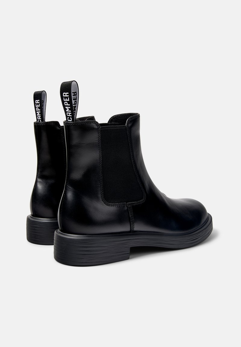 Pair of black leather ankle boots with elastic side panels, branded pull tabs, and low ridged heels on a white background.