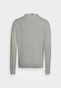 Grau gestrickter Pullover mit langen Ärmeln, Rundhalsausschnitt und gerippten Bündchen. Einfarbige Textur mit einem farblichen Akzent am hinteren Halsausschnitt.