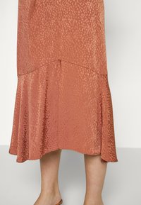 Saia cor ferrugem com um subtil padrão de leopardo, hem ruffle e um design fluido feito de um tecido liso e texturado.