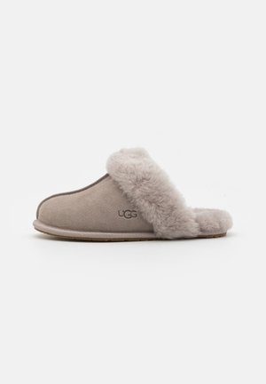 Grey suede slipper with a plush fur lining and open back. Features a sturdy rubber sole and an embossed logo on the side.