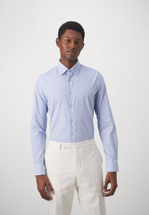 Camicia azzurra a maniche lunghe con colletto button-down, bottoni frontali e vestibilità slim, abbinata a pantaloni color crema.