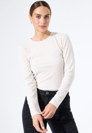 Langarm, lichtbeige geribde top gecombineerd met donkere gestructureerde jeans. Strak ontwerp met een ronde halslijn en slanke mouwen.