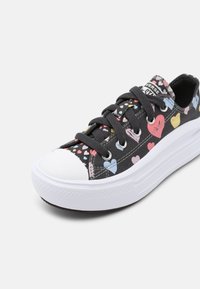 Baskets plateforme noires avec motifs de cœurs multicolores, lacets noirs, bout en caoutchouc blanc et semelle blanche épaisse.