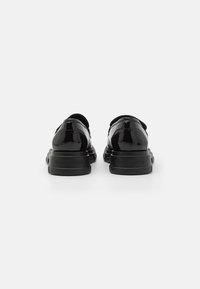 Zwarte lakleren schoenen met een gladde, glanzende afwerking, een ronde neus en een platte zwarte rubberen zool. Merkwaarde zichtbaar op de hak.