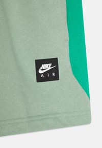 Zielona i morska bluza Nike Air z czarną naszywką, wykonana z bawełny, o gładkiej fakturze i kontrastowym wzorze bocznych paneli.