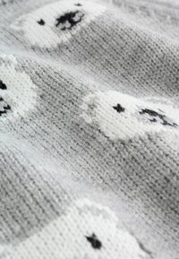 Knitted blanket in gray with white polar bear patterns. Features textured stitches and black accents on the bears’ faces. Soft and cozy material.