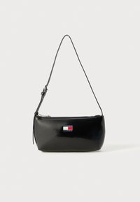 Black patent leather crossbody bag with a zip closure, featuring a logo patch in red, white, and blue, and a thin adjustable strap.
