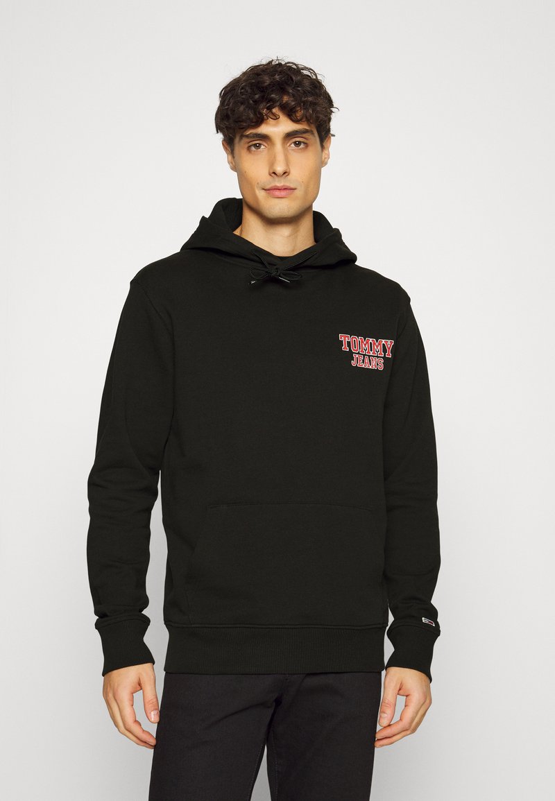 Sudadera negra de algodón, con bolsillo canguro, capucha con cordón y logotipo rojo de "TOMMY JEANS" en el pecho. Puños acanalados.