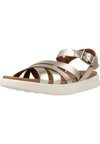 Sandalias de tiras plateadas metálicas con plantilla marrón y suela acolchada blanca; cuentan con correa ajustable en el tobillo y un diseño elegante con cortes.