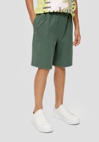 Groene katoenen shorts met een elastische tailleband, uitgerust met zijzakken en een relaxte pasvorm, gecombineerd met witte vetersneakers.