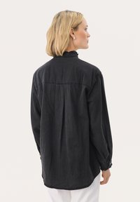 Mustard denim shirts varrukad, pikad varrukad ja ruffled krae. Omavad lahedat sobivust ja peent selja voldi detaili.