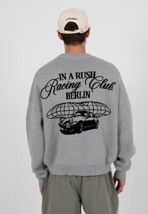 Szary sweter dzianinowy z czarnym nadrukiem samochodu i napisem „IN A RUSH Racing Club BERLIN” na plecach; ściągacze przy rękawach i u dołu.