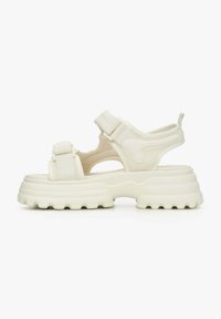 Sandały na platformie w kolorze off-white z syntetycznym wierzchem, regulowanymi paskami i teksturowaną podeszwą dla lepszej przyczepności. Zawierają elementy designu z wycięciami.