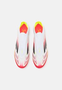 Scarpe slip-on bianche con suola in gradiente rosso-rosa, strisce nere e accenti giallo brillante sul colletto e sulla soletta. Tessuto superiore testurizzato.